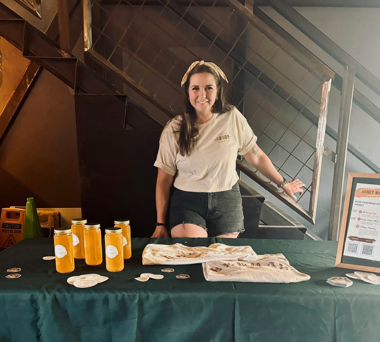 Woman standing behind a table with drinks and food, in an indoor setting.